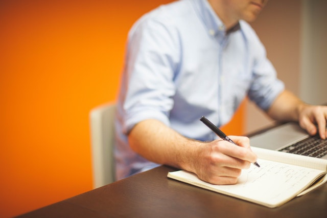 property manager writing notes in orange office